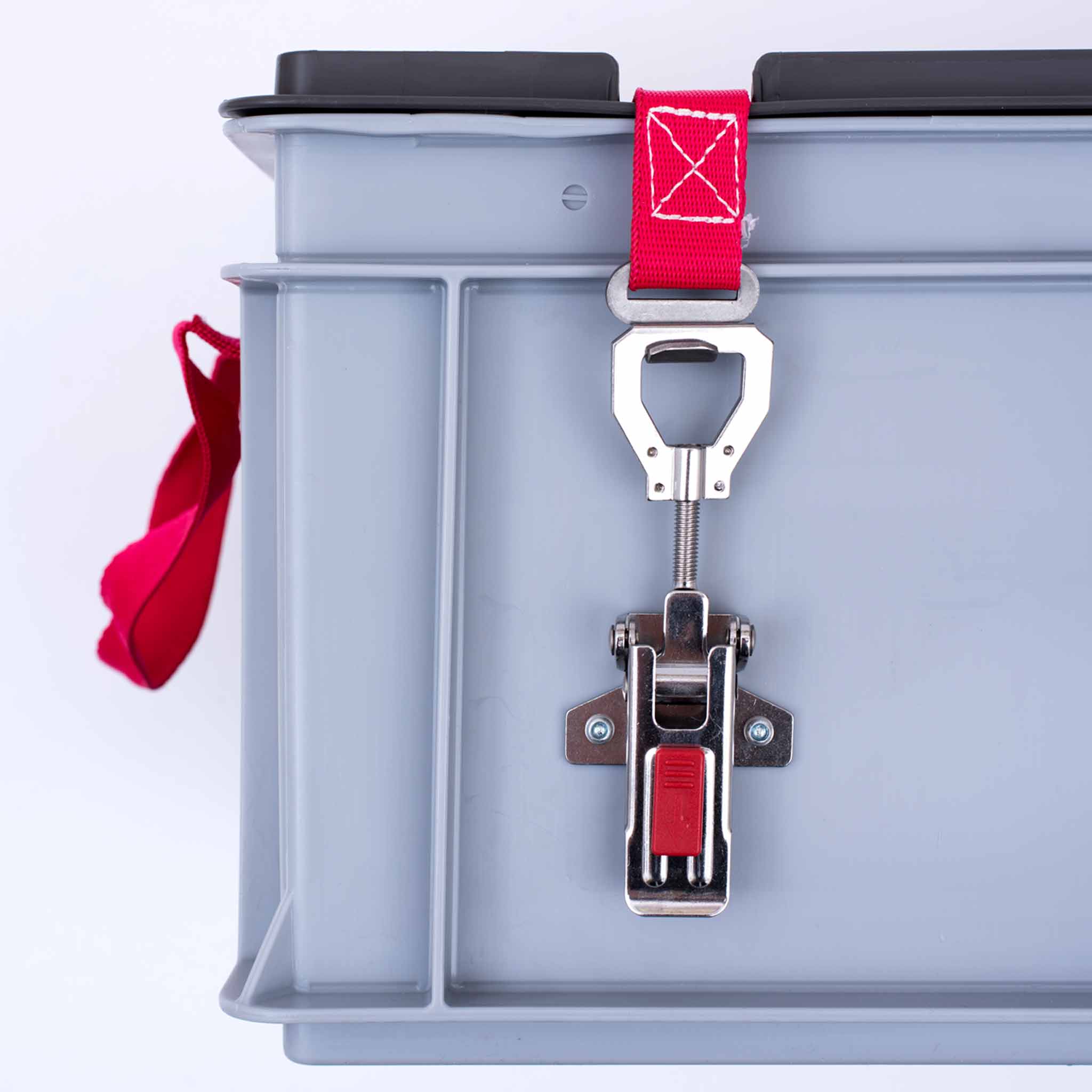 XS-Box 1 Basic Frontansicht auf die linke Seite eines grauen Behälters mit schwarzem Deckel. Das Scharnier ist mit rotem Band verschlossen