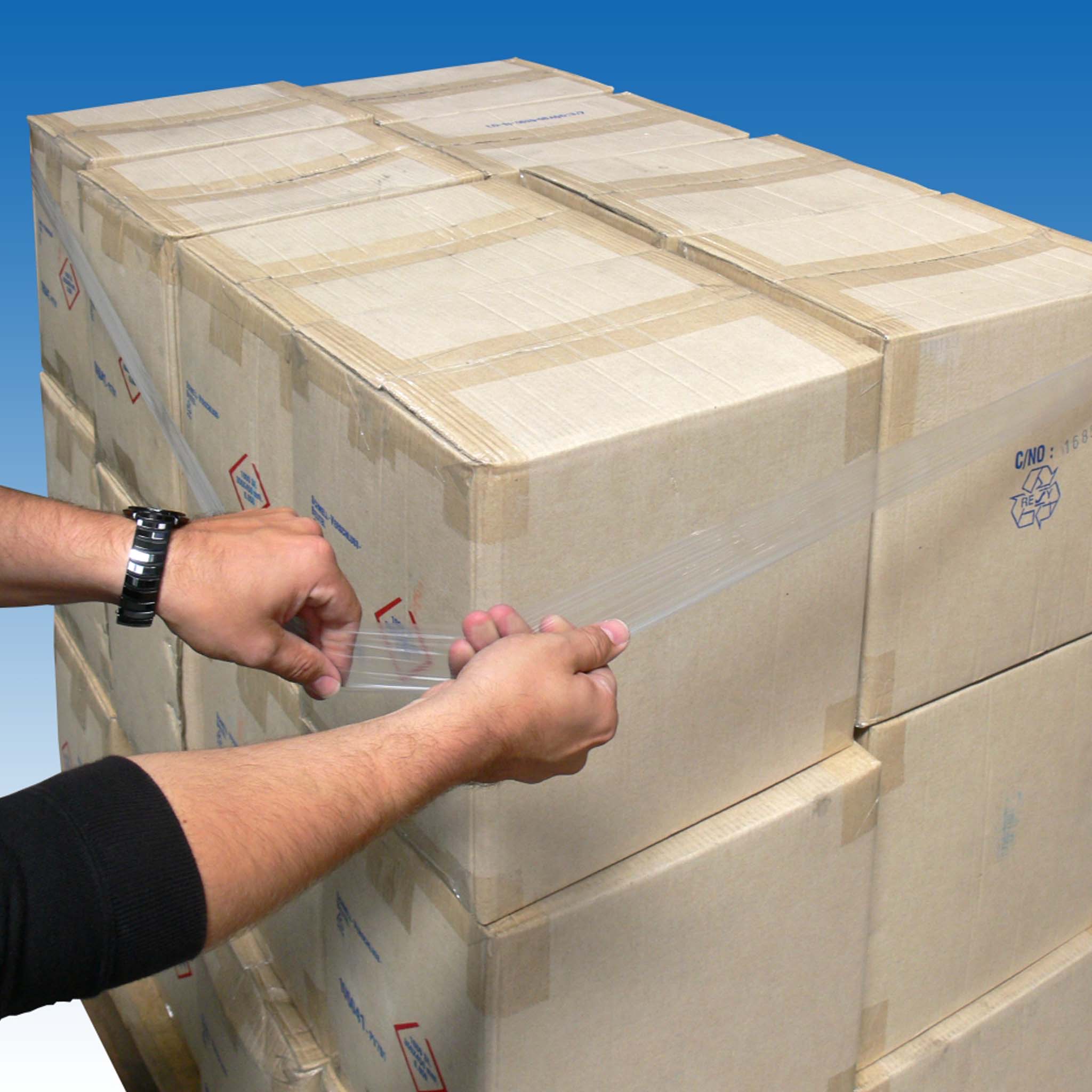 Dehnband zur Palettensicherung Hände, die Dehnband zur Palettensicherung um eine Sendung mit mehreren Kartonagen befestigt