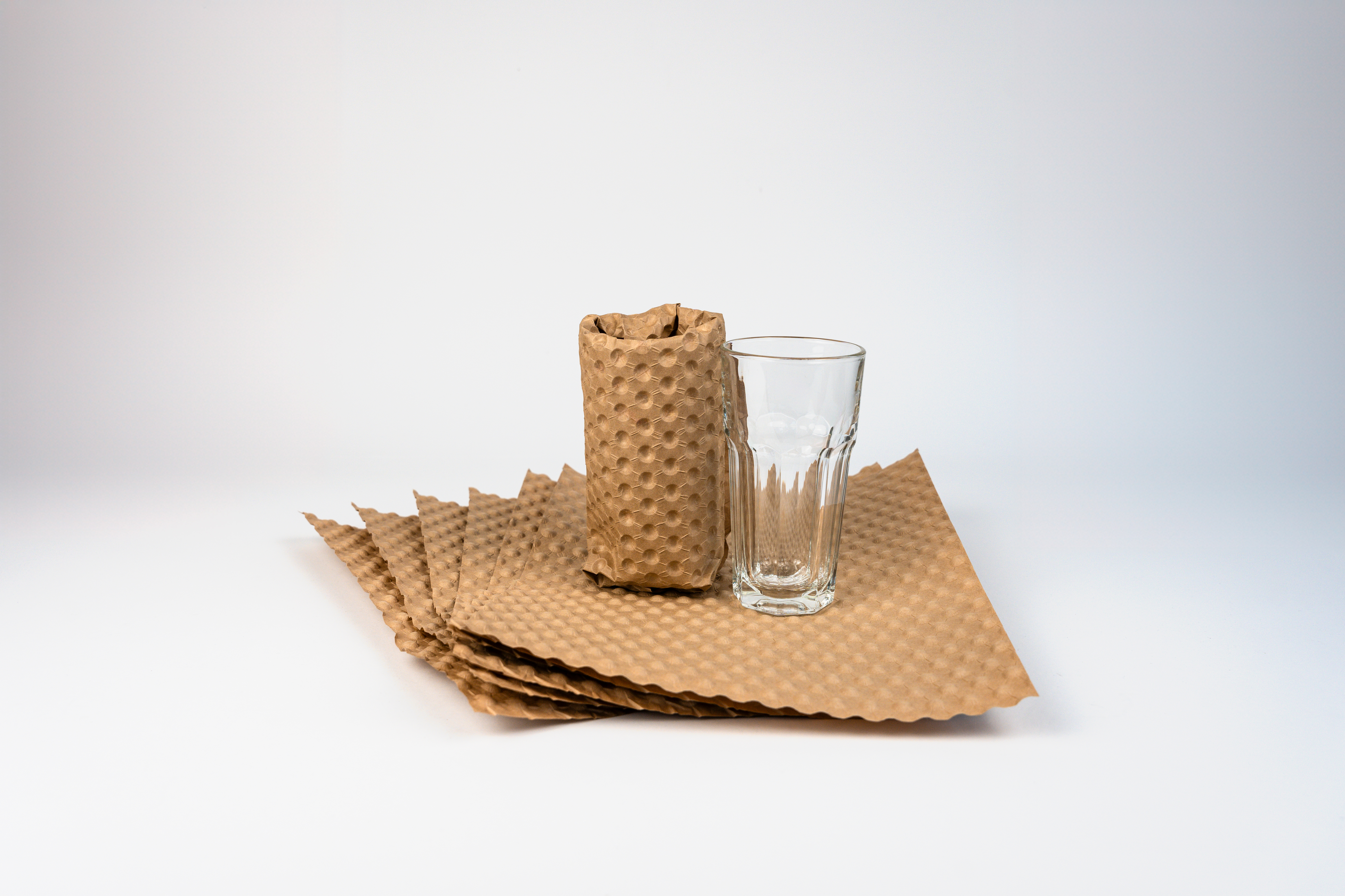 Papair Sheet, Glasverpackung, DB Schenker Ansicht von vorn auf sechs übereinander liegende Sheet, bestehend aus Luftpolsterfolie aus Wellpape. Oben steht ein Glas und ein weiteres, im Material eingewickeltes Glas